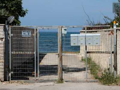 Ancora una volta non riusciamo ad accedere al mare, un cancello grigio con quattro piccole cassette della posta ce lo impedisce, solo i residenti possono aprirlo...
